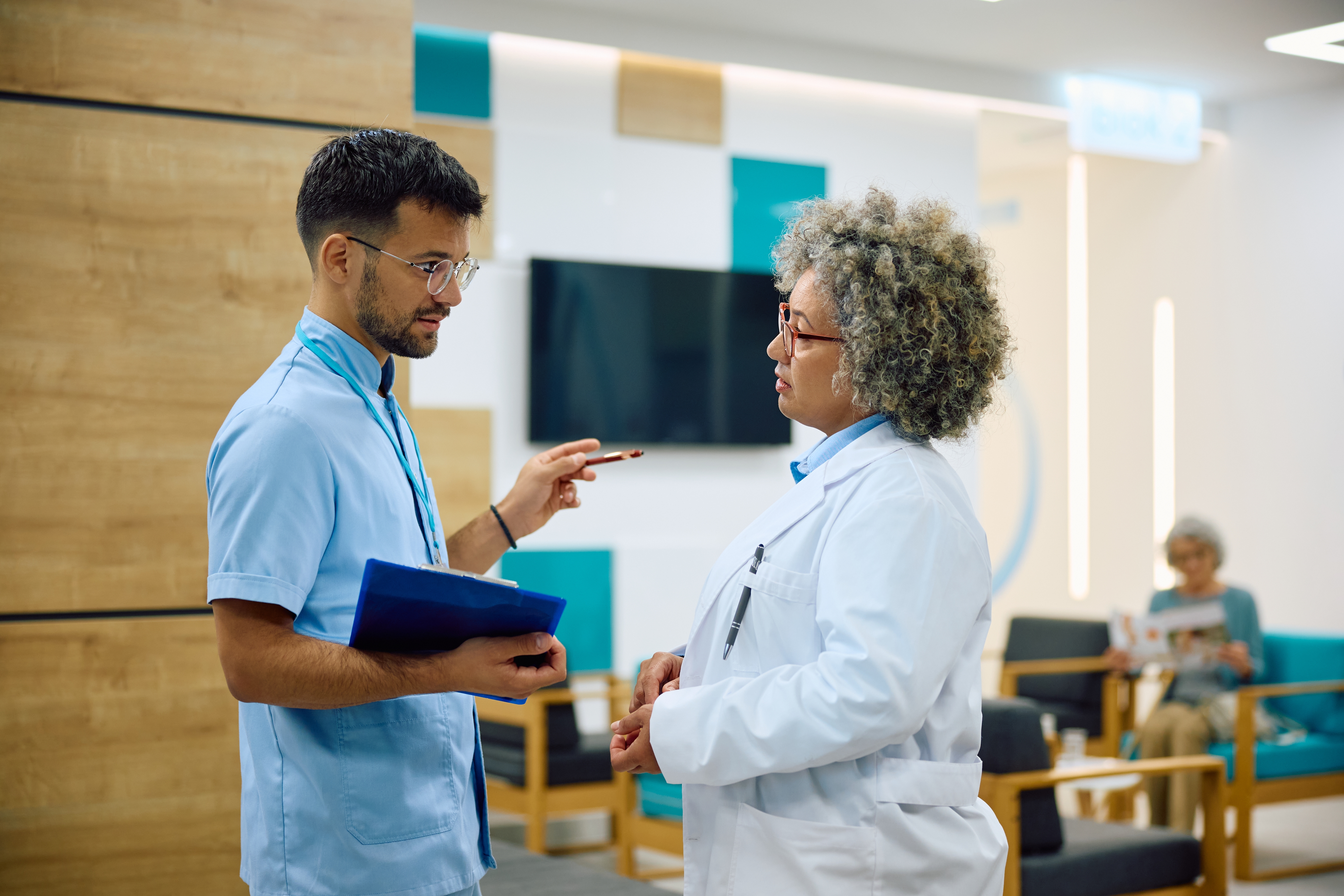 Manager and staff member chat in hospital lobby